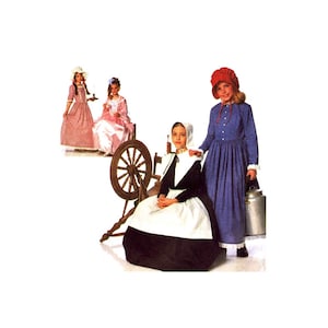 May include: Three girls wearing different styles of colonial dresses. The girl on the left is wearing a pink and white striped dress with a white bonnet. The girl in the middle is wearing a pink dress with a white lace collar and a white headband. The girl on the right is wearing a blue dress with a red bonnet. The girls are standing in front of a spinning wheel.