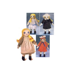 May include: Four handmade rag dolls with blonde hair and painted faces wearing different outfits. The dolls are wearing a white dress with blue trim, a black dress with white trim, a red dress with white trim, and a brown dress with white trim.