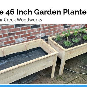 May include: Two wooden garden planters, one with a black liner and the other with green plants growing in it. The planter with plants is 46 inches long and has a wooden base. The text "The 46 Inch Garden Planter" and "Lugar Creek Woodworks" is visible in the image.