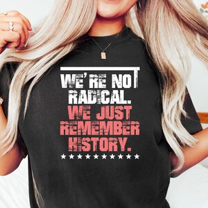 May include: Black t-shirt with white text that reads "We're not radical. We just remember history." with a row of white stars below the text.