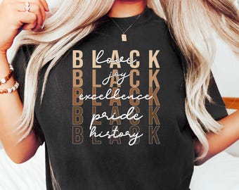 May include: Black t-shirt with the words "Black" and "Loved, Joy, Excellence, Pride, History" in a mix of fonts and colors. The shirt is dark and has a crew neck.