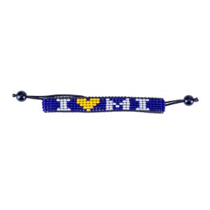 Puede incluir: Una pulsera de cuentas tejidas con fondo azul oscuro, letras blancas que forman I, un símbolo de corazón amarillo y las letras M e I. La pulsera tiene extremos de cordón negro con una cuenta azul oscuro en cada lado para el ajuste.