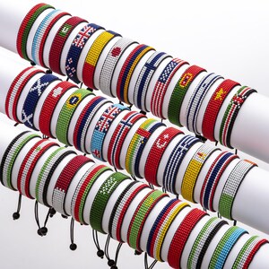 May include: A collection of colorful beaded bracelets featuring various national flags. The bracelets are made with small, colorful beads and are arranged in a row, showcasing a variety of flag designs.