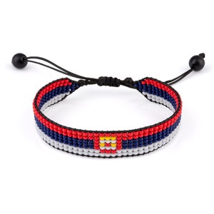 Puede incluir: Un brazalete de cuentas con los colores de la bandera de Colorado. El brazalete es ajustable con un cordón negro y cuentas negras en los extremos.