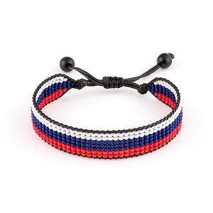Op de afbeelding: Een zwarte kralen armband met rode, witte en blauwe strepen. De armband is verstelbaar met zwarte koordsluitingen.