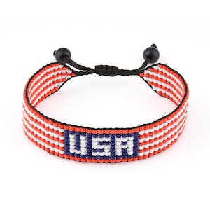 May include: A red, white, and blue beaded bracelet with the word "USA" in blue beads. The bracelet has a black cord with black beads on each end.