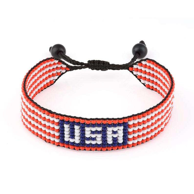 May include: A red, white, and blue beaded bracelet with the word "USA" in blue beads. The bracelet has a black cord with black beads on each end.