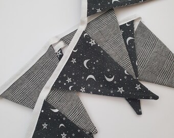 May include: A black and white bunting with a moon and star pattern. The bunting is made of fabric and has a white trim.