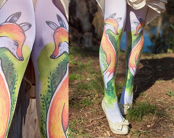 May include: White tights with a fox design printed on them. The fox is orange and yellow with green foliage surrounding it. The tights are worn by a person standing in a grassy area.