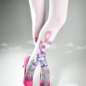May include: White tights with a colorful bunny and floral design. The tights are paired with bright pink high heels. The bunny is wearing a blue outfit and is surrounded by flowers. The image has a whimsical and playful theme.