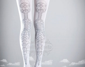 May include: White tights with a black skeleton design printed on the legs. The design includes a skull at the top of the skeleton. The tights are worn by a person with black shoes.