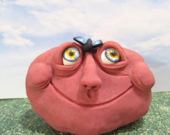 Red Rock smiling face with a little blue butterfly garden decoration