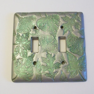 Collage of leaves in silver and metallic green light switch cover