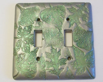 Collage of leaves in silver and metallic green light switch cover