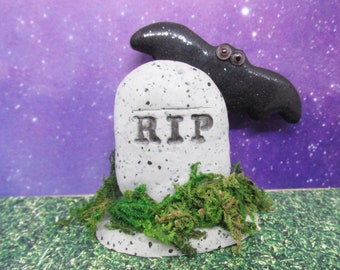 Miniature RIP headstone with a black bat and moss