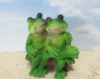 Pair of miniature cuddling frogs on a park bench