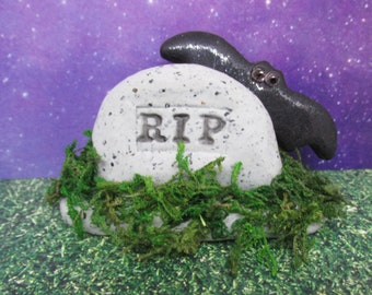 Miniature RIP headstone with a black bat and moss