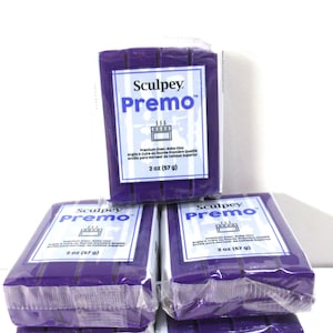 May include: Several packages of purple Sculpey Premo oven-bake clay are stacked. Each package is wrapped in clear plastic and features a white label with the brand name, product name, and weight: 2 oz (57 g).