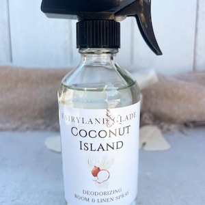 May include: Clear glass spray bottle with a black nozzle and a white label. The label reads "Fairyland Glade Coconut Island" with a coconut illustration. The bottle contains 8 oz / 237 ml of deodorizing room and linen spray.
