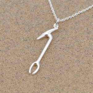 Op de afbeelding: Een zilveren ketting met een hanger in de vorm van een houweel. De hanger hangt aan een zilveren ketting.