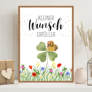 Pode incluir: Uma impressão emoldurada com o texto "Kleiner Wunsch Erfüller" e um design em aquarela de um trevo de quatro folhas. O trevo contém uma nota de 50 euros. A parte inferior da impressão apresenta um prado de flores silvestres colorido.