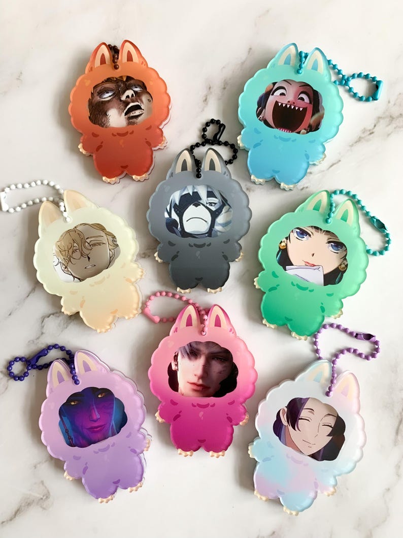 May include: A selection of acrylic keyrings in various colours. Each keyring has a cartoon animal design with a face inside. The keyrings are in shades of orange, blue, green, pink, purple, and light blue, each with a different image.