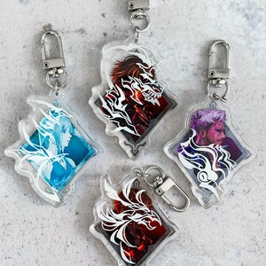 May include: Four clear acrylic keychains featuring different character designs. Each keychain has a white silhouette of a character against a colourful background. The characters include a woman with wings, a man with a beard, a man with horns, and a woman with a crown.