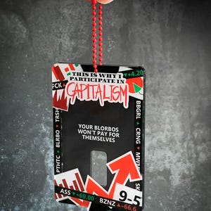 May include: A black and red keychain with the text "THIS IS WHY I PARTICIPATE IN CAPITALISM" and an arrow pointing upwards. The keychain also has the text "YOUR BLORBOS WON'T PAY FOR THEMSELVES".