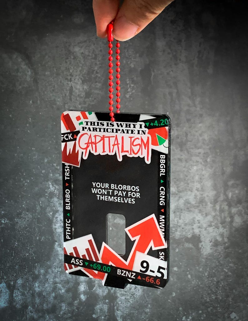 May include: A black and red keychain with the text "THIS IS WHY I PARTICIPATE IN CAPITALISM" and an arrow pointing upwards. The keychain also has the text "YOUR BLORBOS WON'T PAY FOR THEMSELVES".