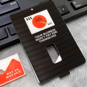 May include: Black card with a white circle graph showing expenses and rent. The text on the card reads "$$$ BLORBO EXPENSES RENT YOUR BLORBOS WON'T PAY FOR THEMSELVES".