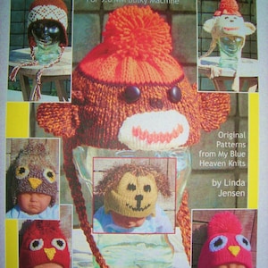 May include: A book cover featuring a variety of knitted animal hats with ear flaps. The book title is "Ear-Flaps and Animal Hats" and the text "For 9.0 MM Bulky Machine" is below the title. The book cover also includes the text "Original Patterns from My Blue Heaven Knits by Linda Jensen".
