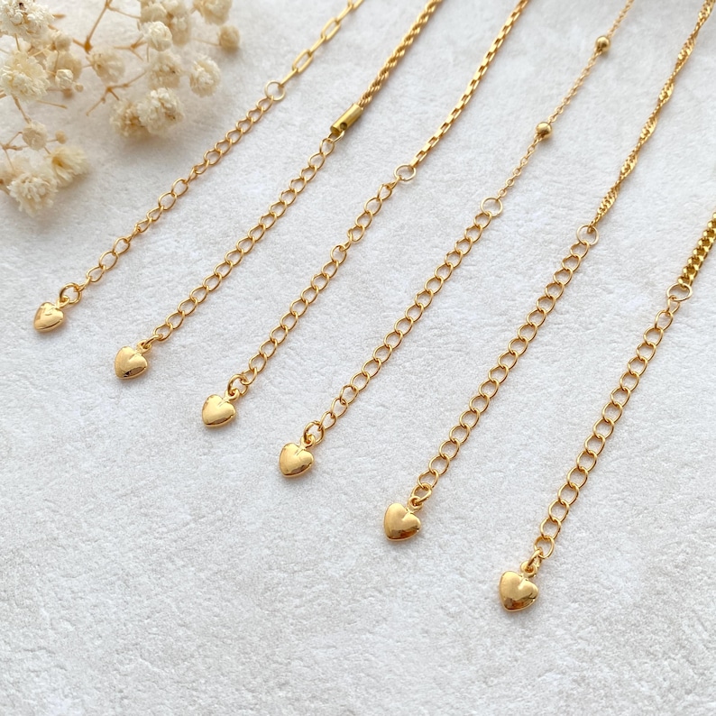 May include: Six gold chain extenders with heart-shaped charms. The chains are different lengths and styles.