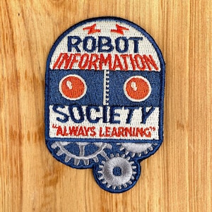 May include: A blue and white embroidered patch with the text "Robot Information Society" and the phrase "Always Learning". The patch features a robot face with red eyes and gears.