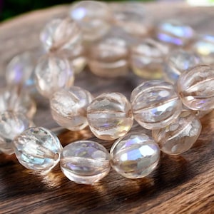 May include: A strand of iridescent clear glass beads with a faceted, ribbed design. The beads are strung together on a clear thread.