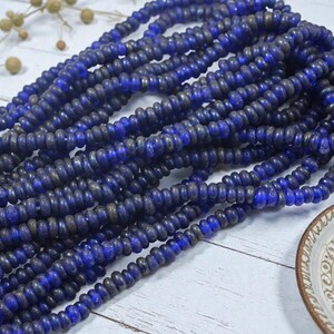May include: Strands of deep blue beads with a slightly irregular shape, creating a textured appearance. The beads are arranged in multiple strands, suggesting a necklace or craft supply. The color is a rich, saturated blue.
