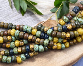 May include: A strand of colorful glass beads in shades of brown, yellow, blue, and green. The beads are round and have a speckled or marbled appearance.