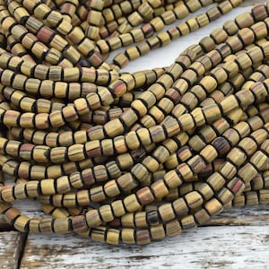 May include: A strand of brown, black, and red striped glass beads. The beads are square shaped and have a matte finish.