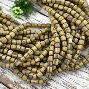 May include: A strand of brown and white striped wooden beads. The beads are square shaped and have a matte finish.