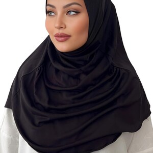 May include: A black jersey hijab with a gathered, draped style. The hijab is made of a soft, stretchy fabric.