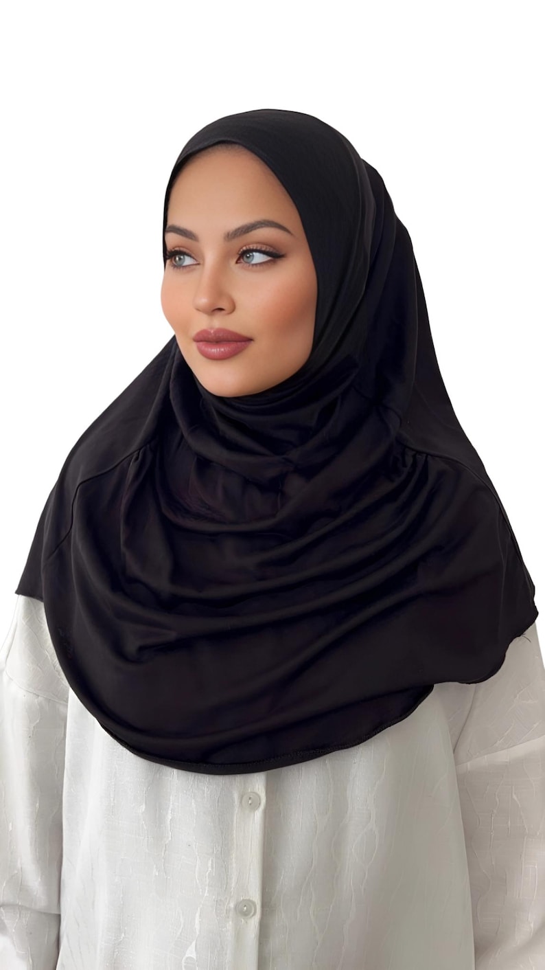 May include: A black jersey hijab with a gathered, draped style. The hijab is made of a soft, stretchy fabric.
