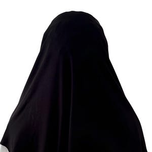 May include: A black hijab made of a soft, flowing fabric. The hijab is draped over the head and shoulders, with the edges falling loosely around the neck.
