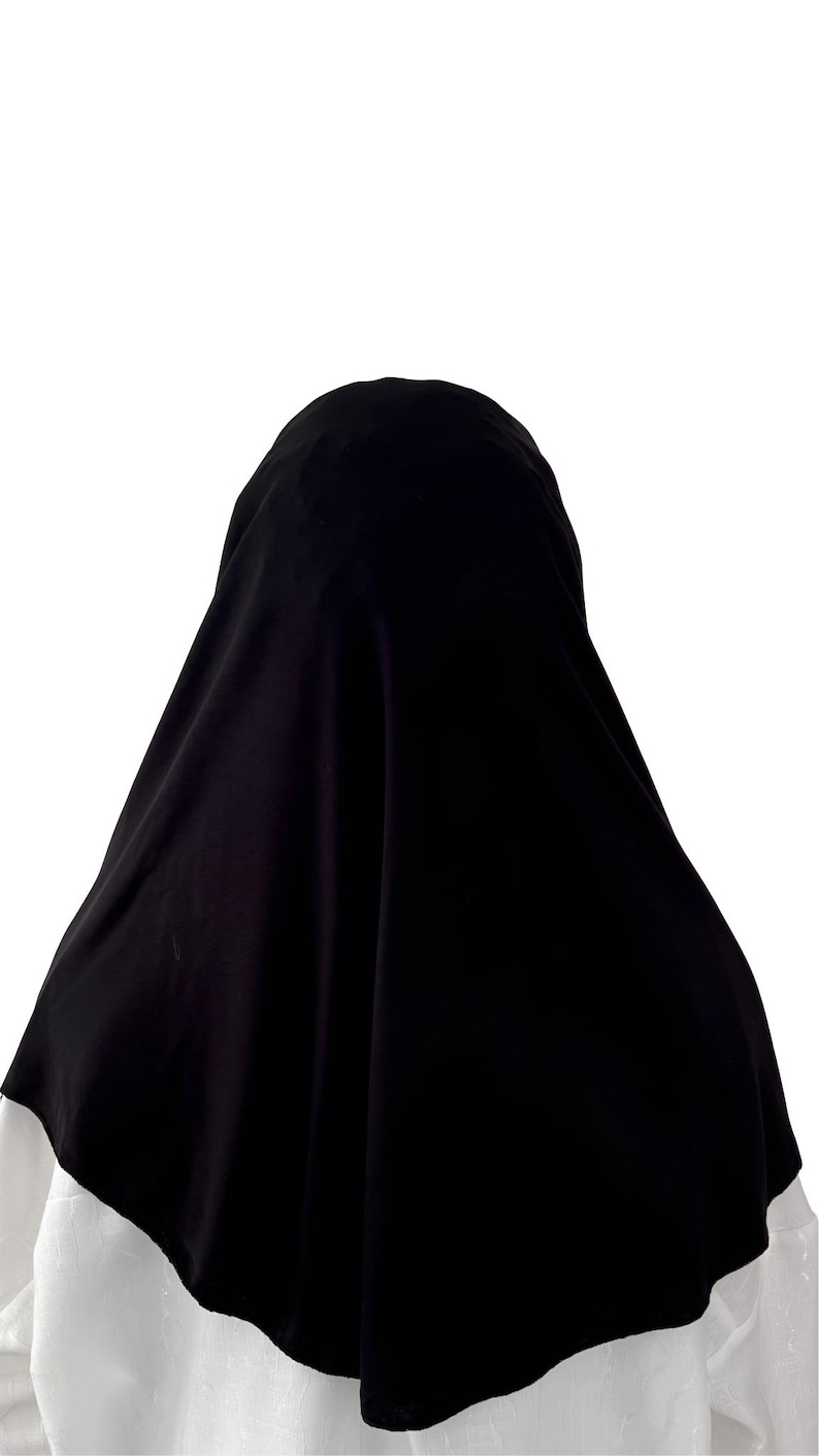 May include: A black hijab made of a soft, flowing fabric. The hijab is draped over the head and shoulders, with the edges falling loosely around the neck.