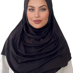 May include: A black jersey knit hijab with a gathered, draped style. The hijab is made of a soft, stretchy fabric.