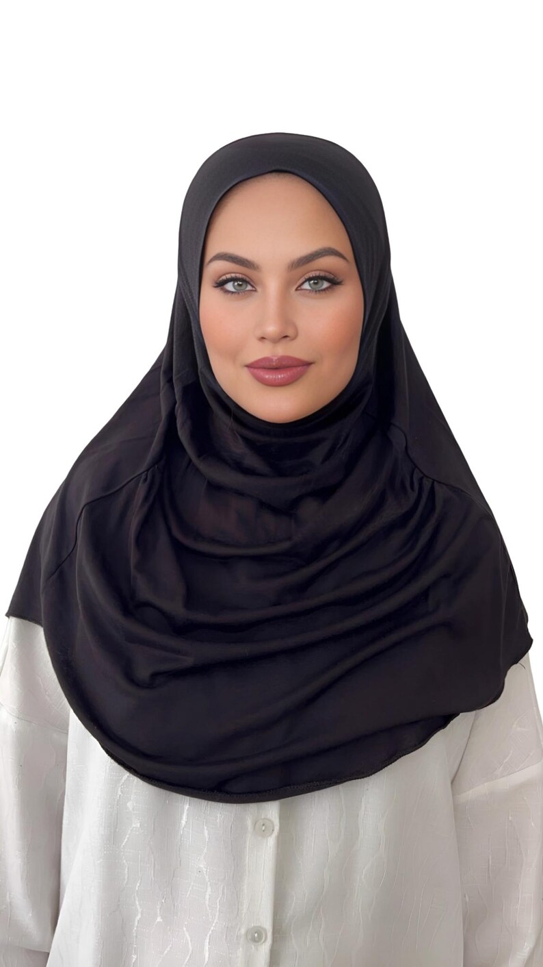 May include: A black jersey knit hijab with a gathered, draped style. The hijab is made of a soft, stretchy fabric.