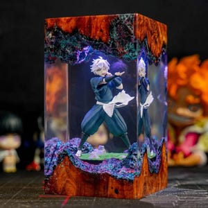 May include: A decorative resin block featuring a figurine of a character in a blue outfit with white accents. The block has a wooden texture with red, orange, and blue hues. The figurine is in a dynamic pose, with a mirrored reflection.