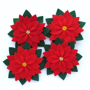 May include: Four red felt poinsettia flowers with green felt leaves and gold bead centers.