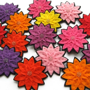 May include: A collection of felt flower brooches in various colors, including red, orange, yellow, pink, and purple. Each flower has a beaded center and is surrounded by layers of felt petals.