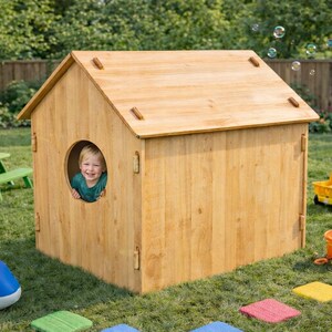 May include: A wooden playhouse with a round window, a child peeking out, and a pitched roof. The playhouse is surrounded by toys, including a yellow dump truck, a blue whale-shaped sprinkler, and a green picnic table. Bubbles float in the air.