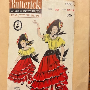 May include: Vintage Butterick printed pattern featuring a colorful illustration of a woman and a girl in flamenco-style dresses. The dresses are red with tiered ruffles, paired with yellow tops and black accents. The pattern includes the text "Butterick Printed Pattern".