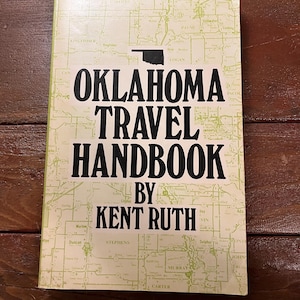 May include: A vintage travel handbook titled "Oklahoma Travel Handbook by Kent Ruth." The cover features a map of Oklahoma in light green over a cream background. The title is in large black letters, with the state outline above.